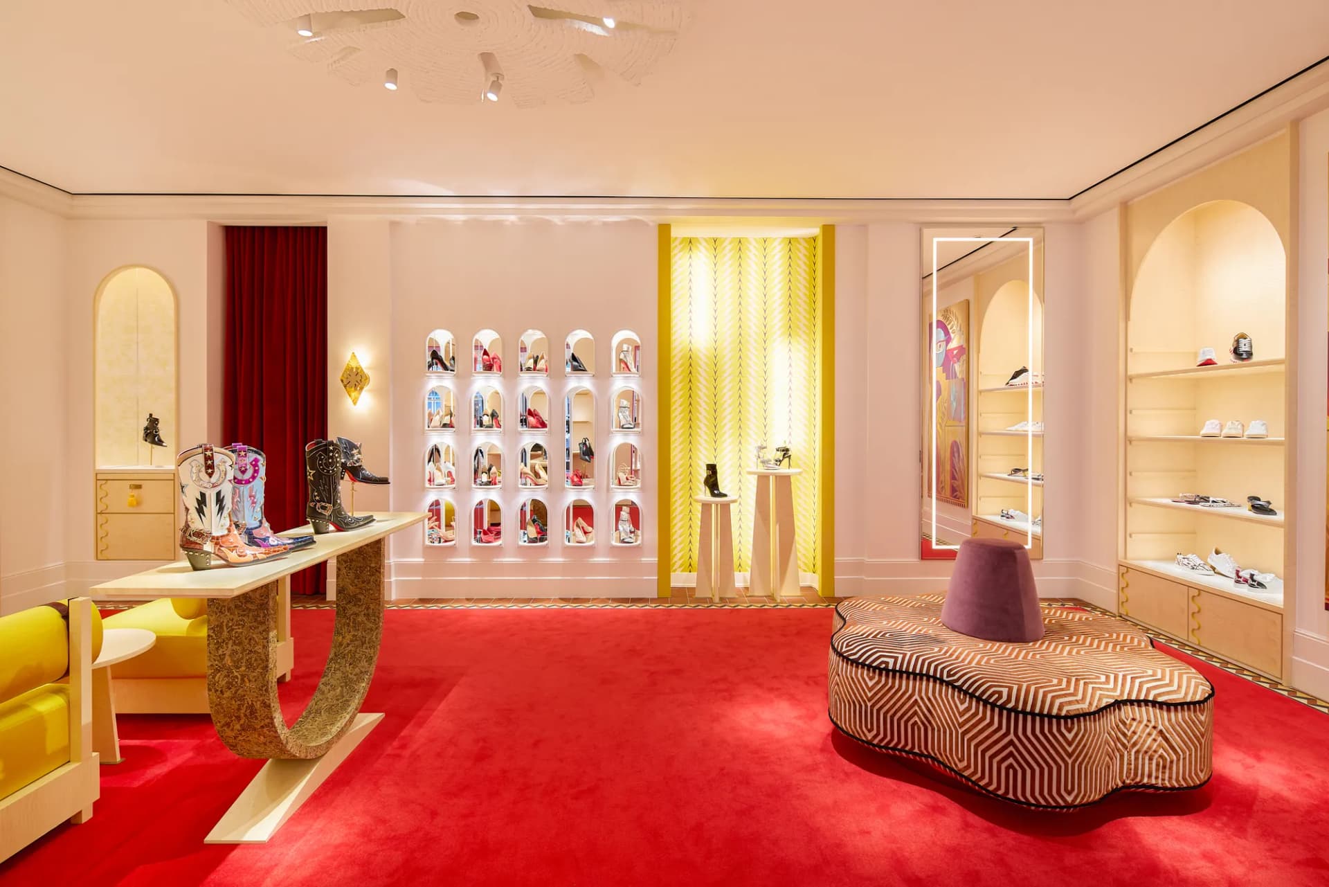 Wall of lit shoe niches with a gold chair and a patterned ottoman