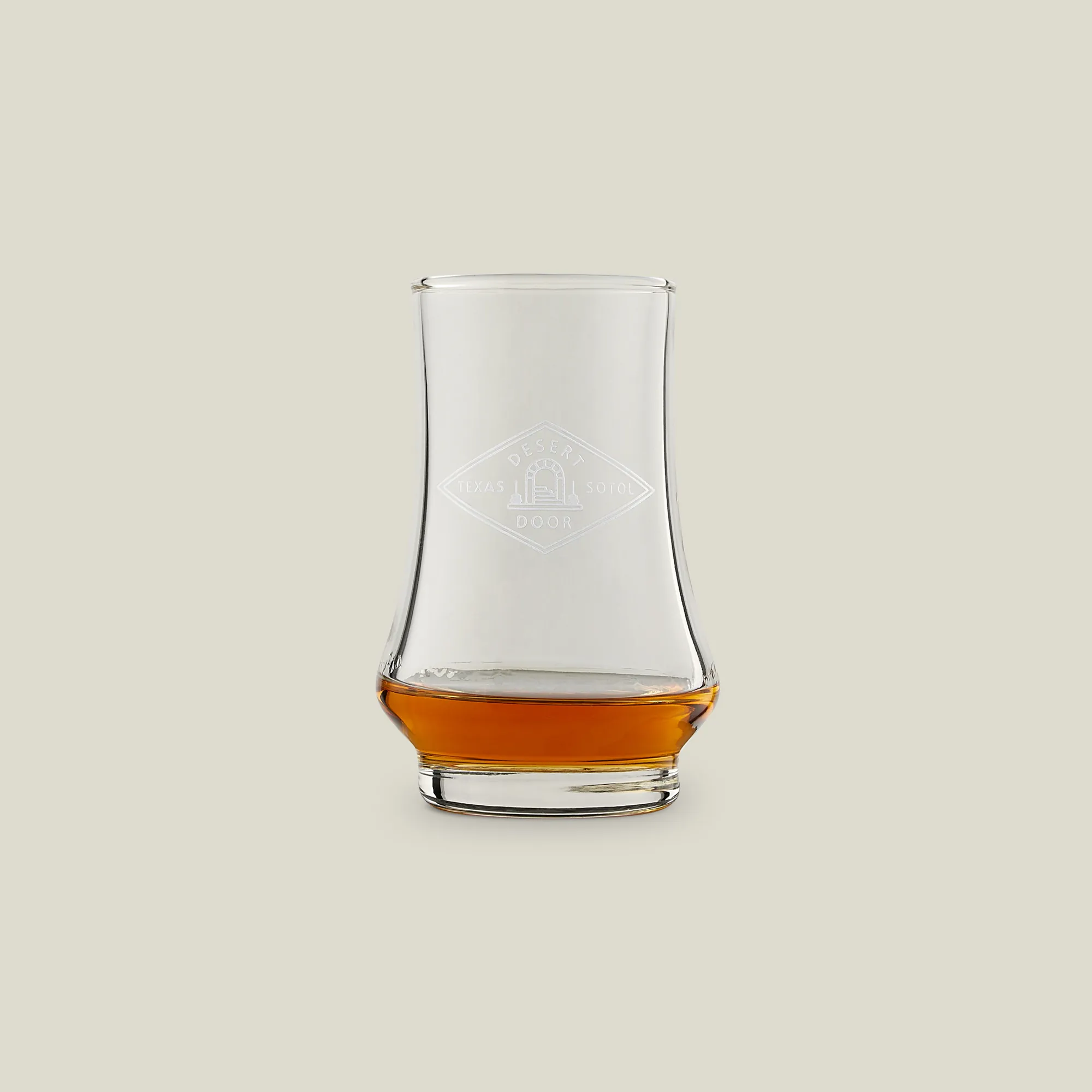 Glencairn glass of amber sotol on a neutral background