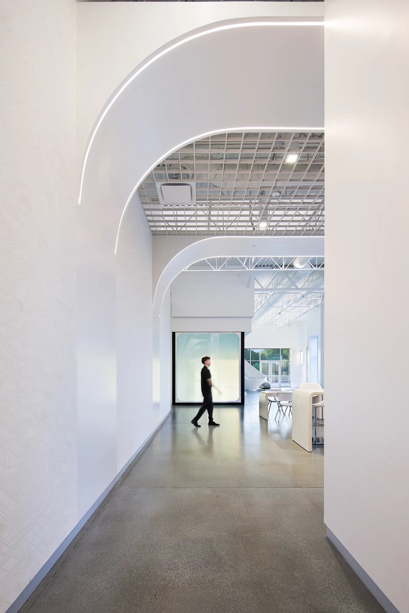 Arched white corridor with a figure walking through
