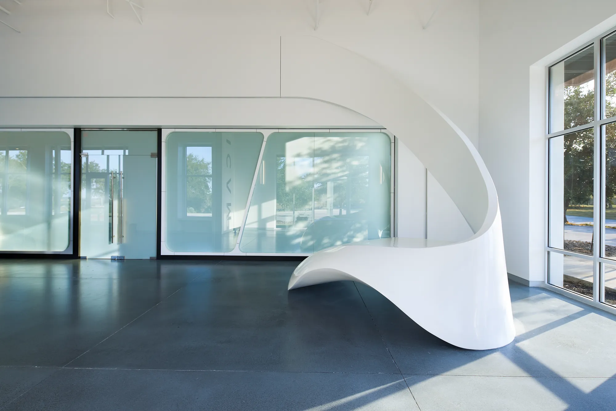 HICAM lounge with a sculpted white desk and a dramatic curving wall
