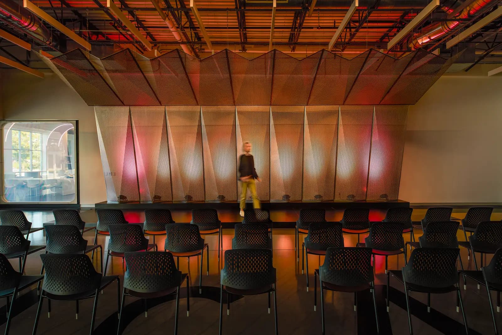 Training room with a red-lit acoustic wall and rows of chairs