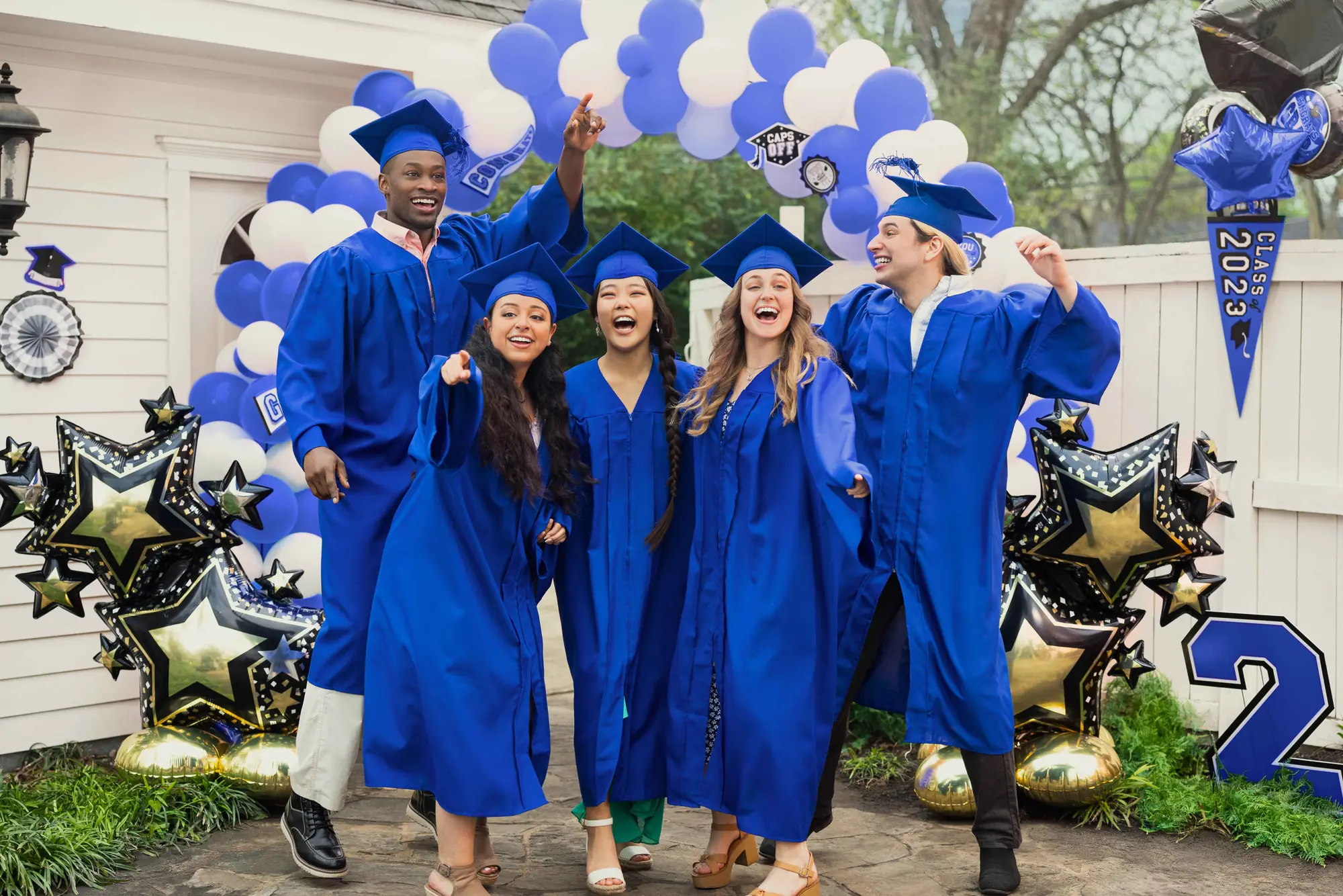Graduates celebrating in front of a blue and white balloon wall