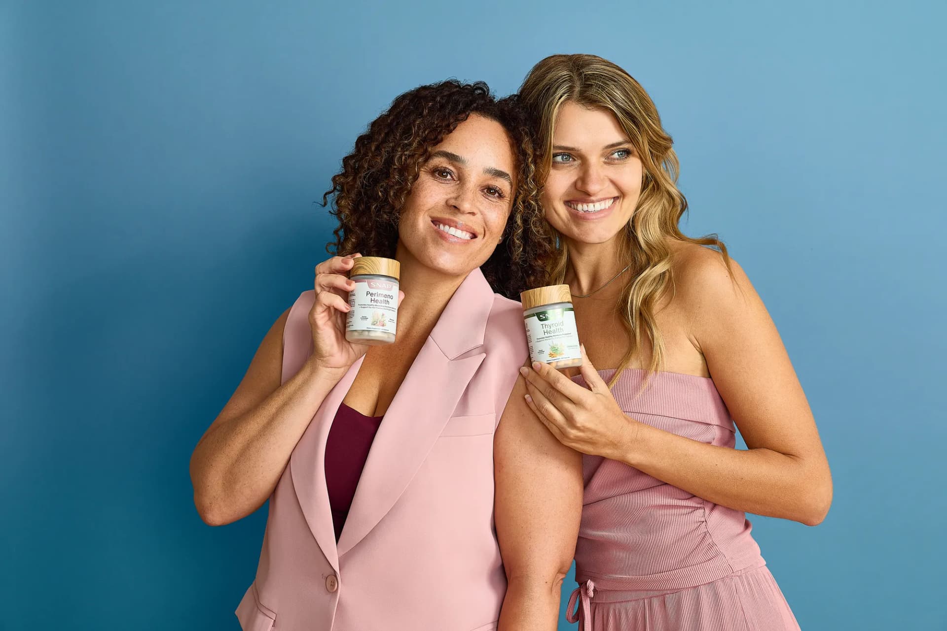Two models in pink holding SNAP Supplements bottles