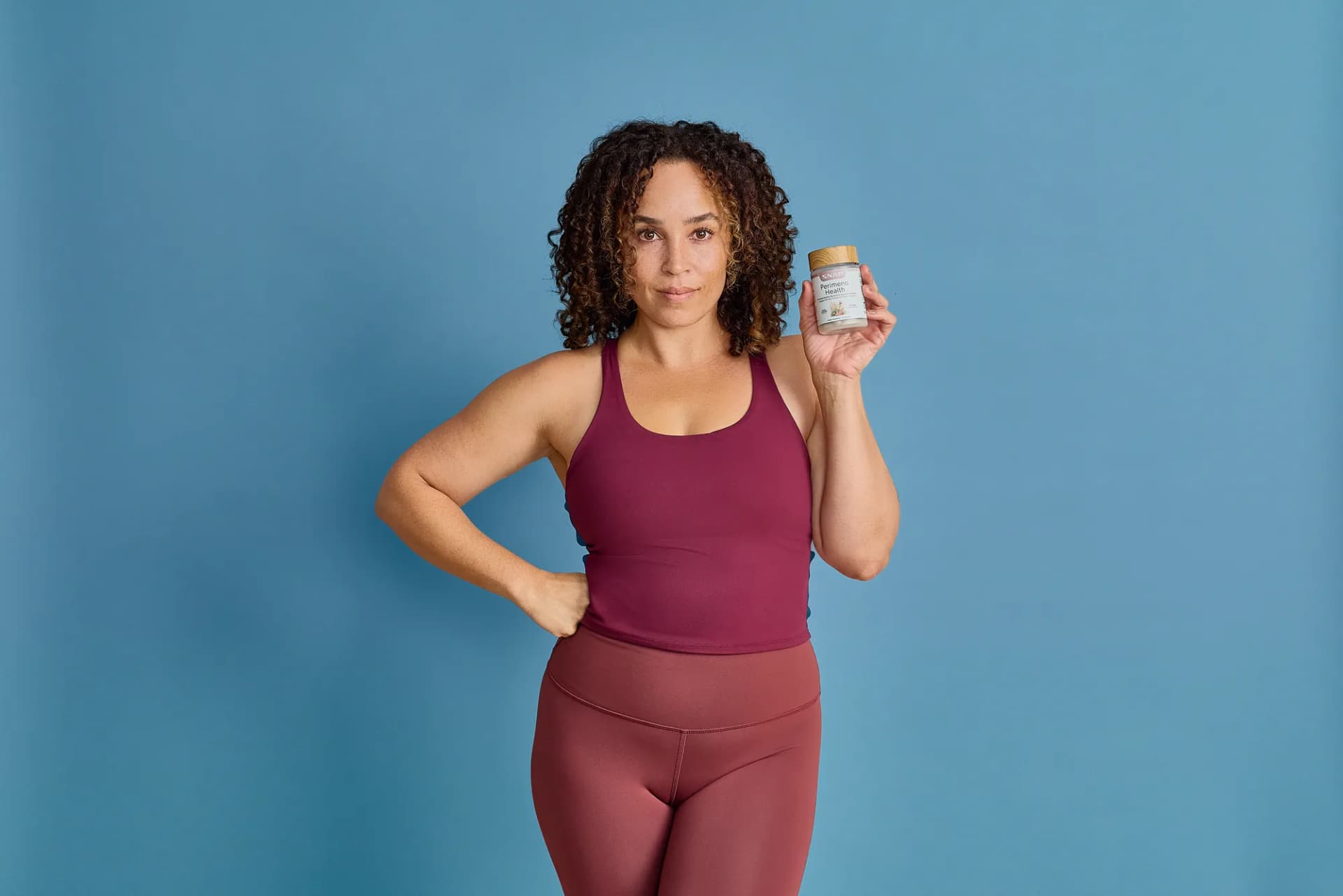 Model in a maroon set holding a SNAP Supplements bottle