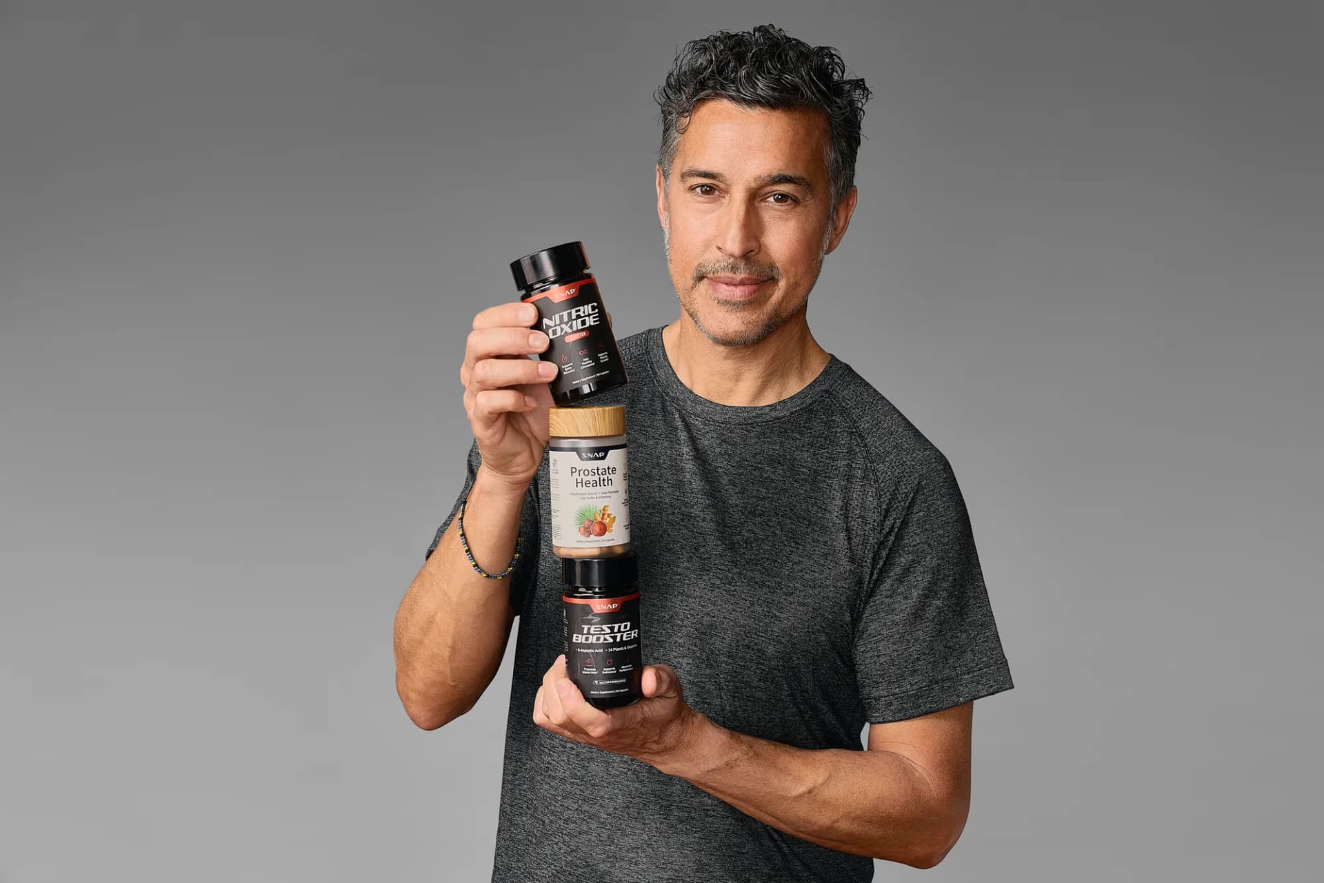 Model holding two SNAP Supplements bottles on a gray backdrop
