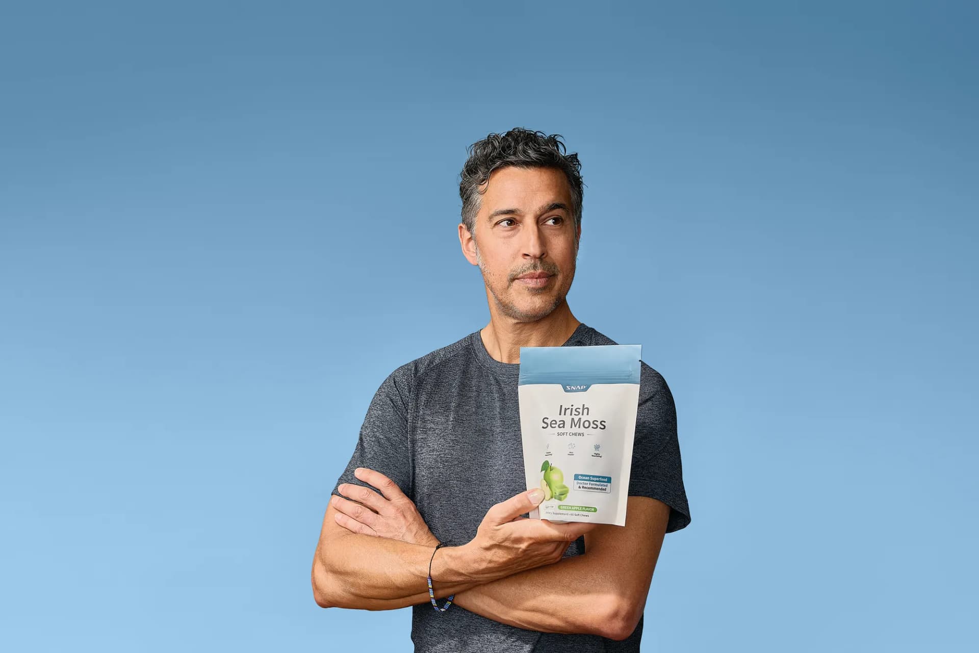 Model holding a SNAP Supplements pouch with arms crossed