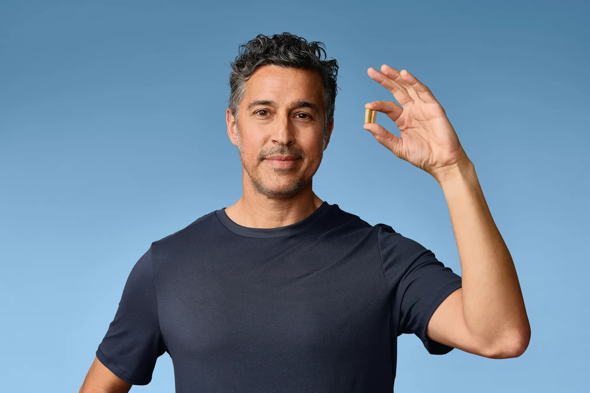 Model smiling and waving on a sky-blue backdrop from the March test shoot