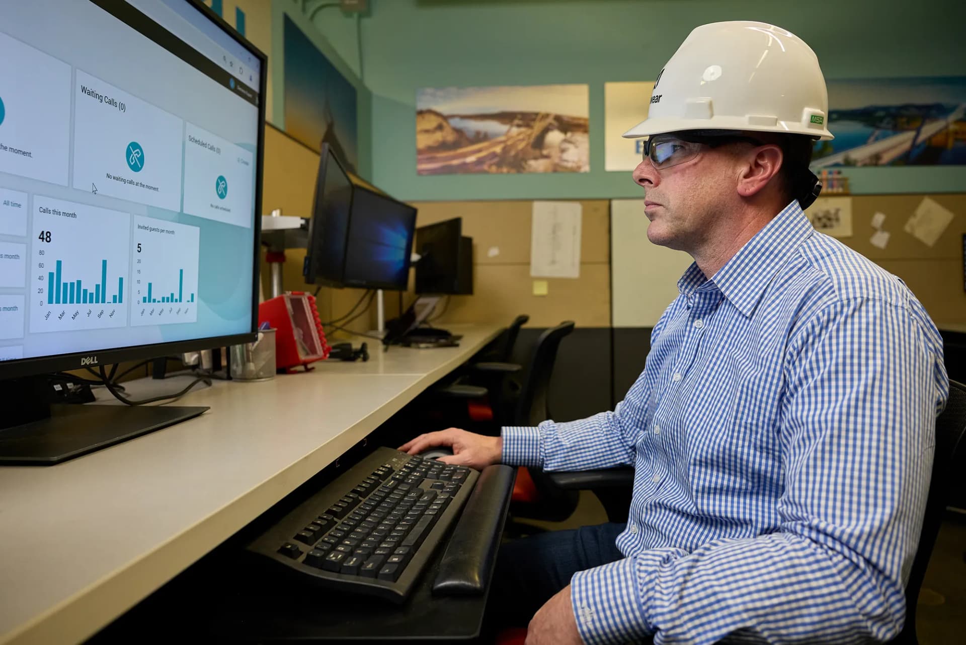 Engineer in a hard hat working at a monitoring desk