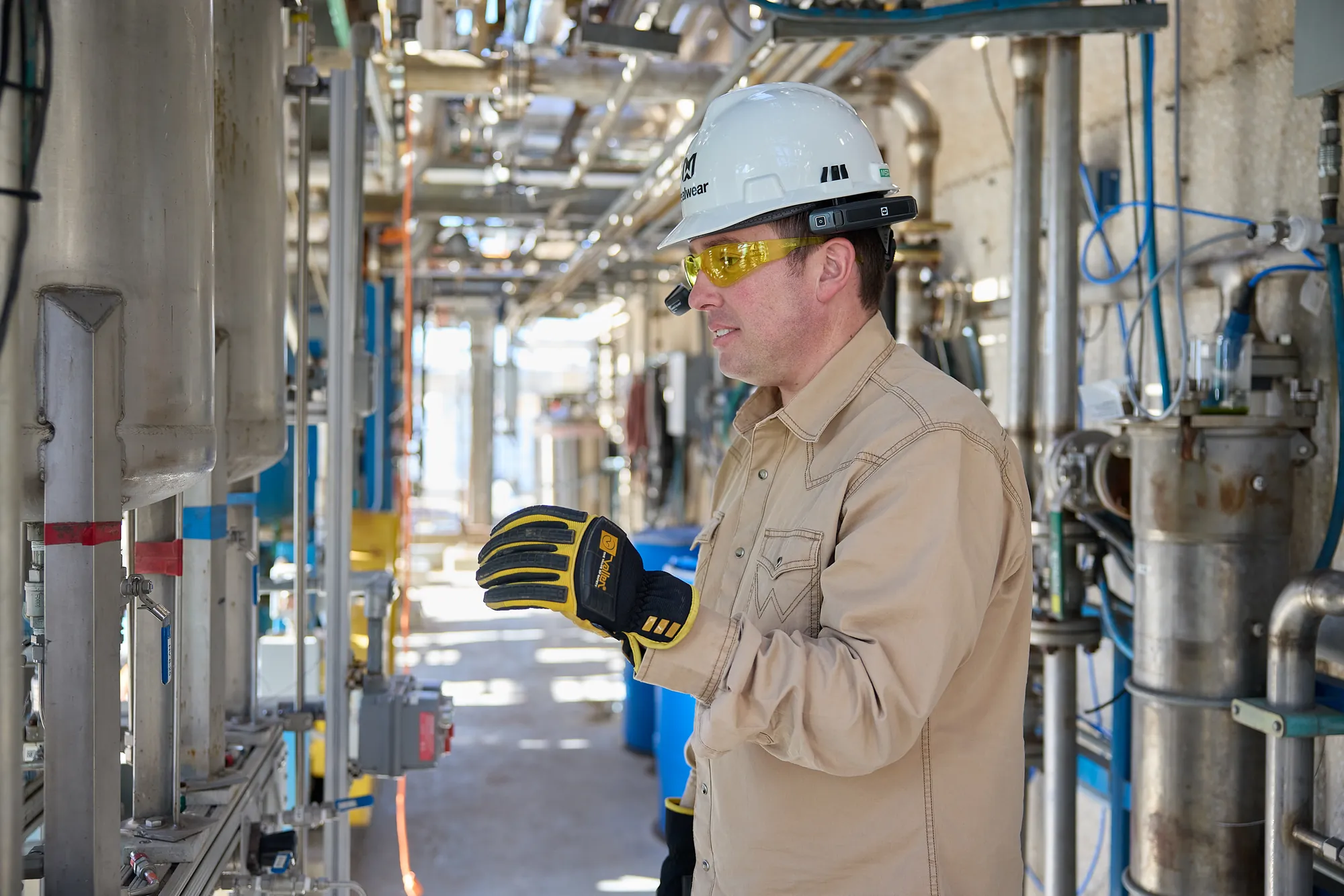 Technician in a hard hat and gloves inside an industrial facility
